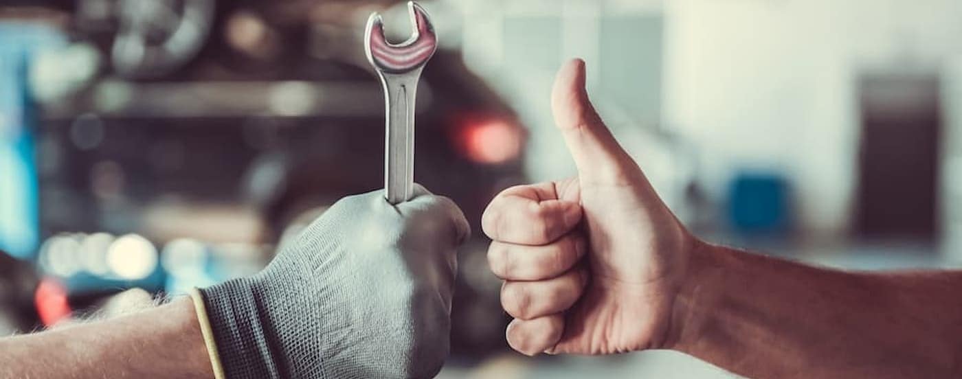 Two people are shown holding a wrench and giving a thumbs up at a Ram service center.