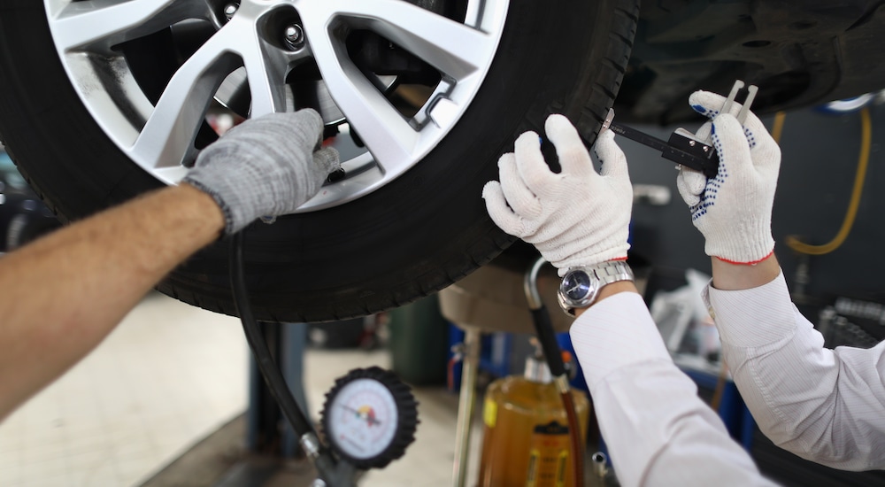 Mechanics inspecting tire tread on a vehicle at a Jeep service center.