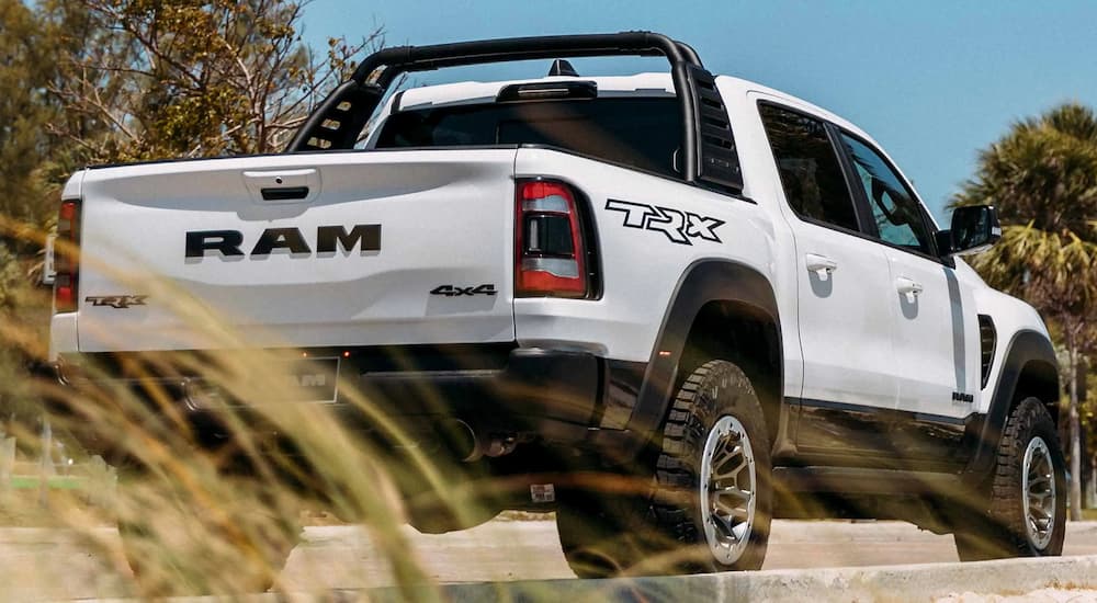 A white 2022 Ram 1500 TRX is parked in a lot near flowing grass.