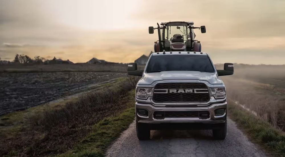 A silver 2024 Ram 2500 Tradesman is shown towing a tractor.