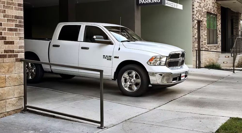 A white 2024 Ram 1500 Classic Tradesman is shown leaving a parking garage after looking at commercial vehicles for sale.