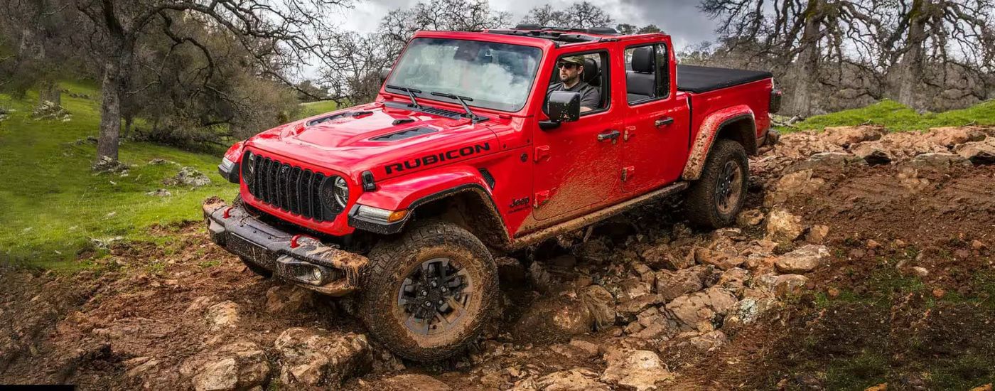 A red 2024 Jeep Gladiator Rubicon is shown off-roading.