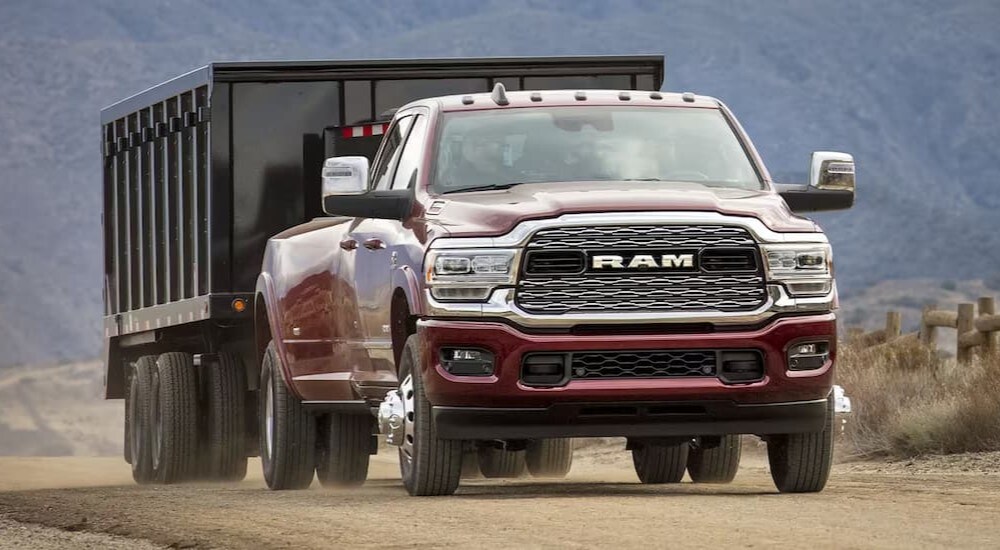 A red 2024 Ram 3500 towing a trailer off-road.