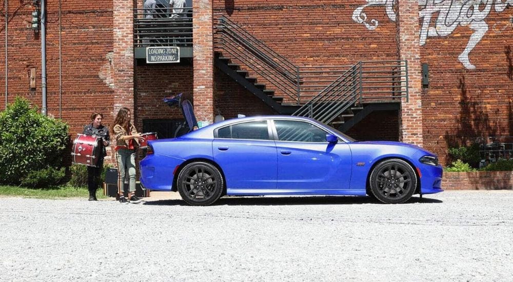 A blue 2020 Dodge Charger is shown in front of a brick building.