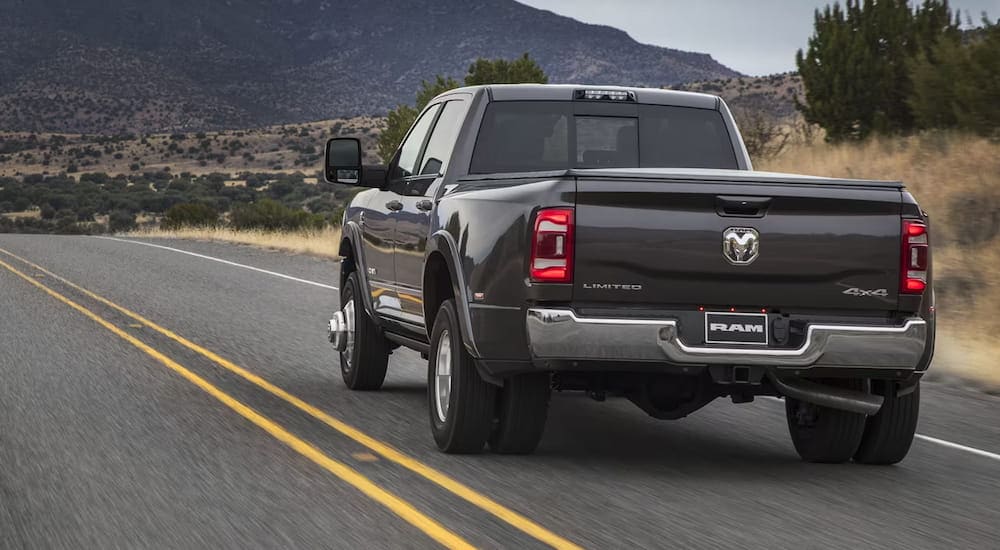 Rear view of a black 2024 Ram 3500 Limited driving.