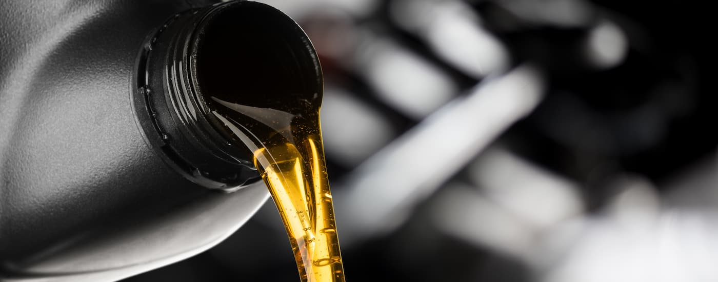 A large bottle of engine oil is being poured into a vehicle getting Jeep service done.