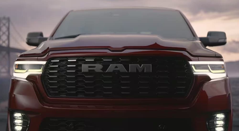 Close-up of the grille and headlights on a red 2025 Ram 1500 Tungsten at a dealer with commercial vehicles for sale near Lancaster.