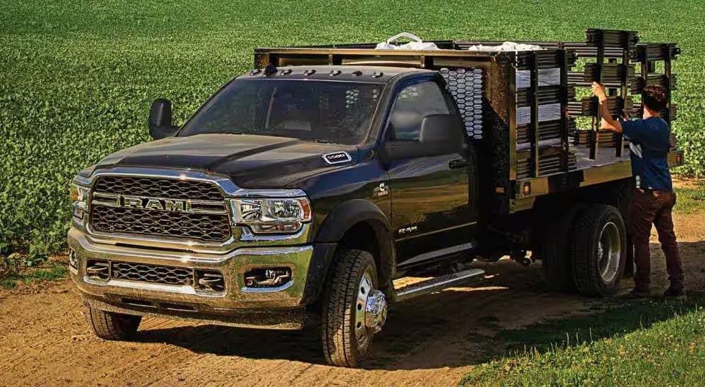 A black 2024 Ram 5500 Tradesman Chassis Cab with Stake Bed Upfit parked in a field.