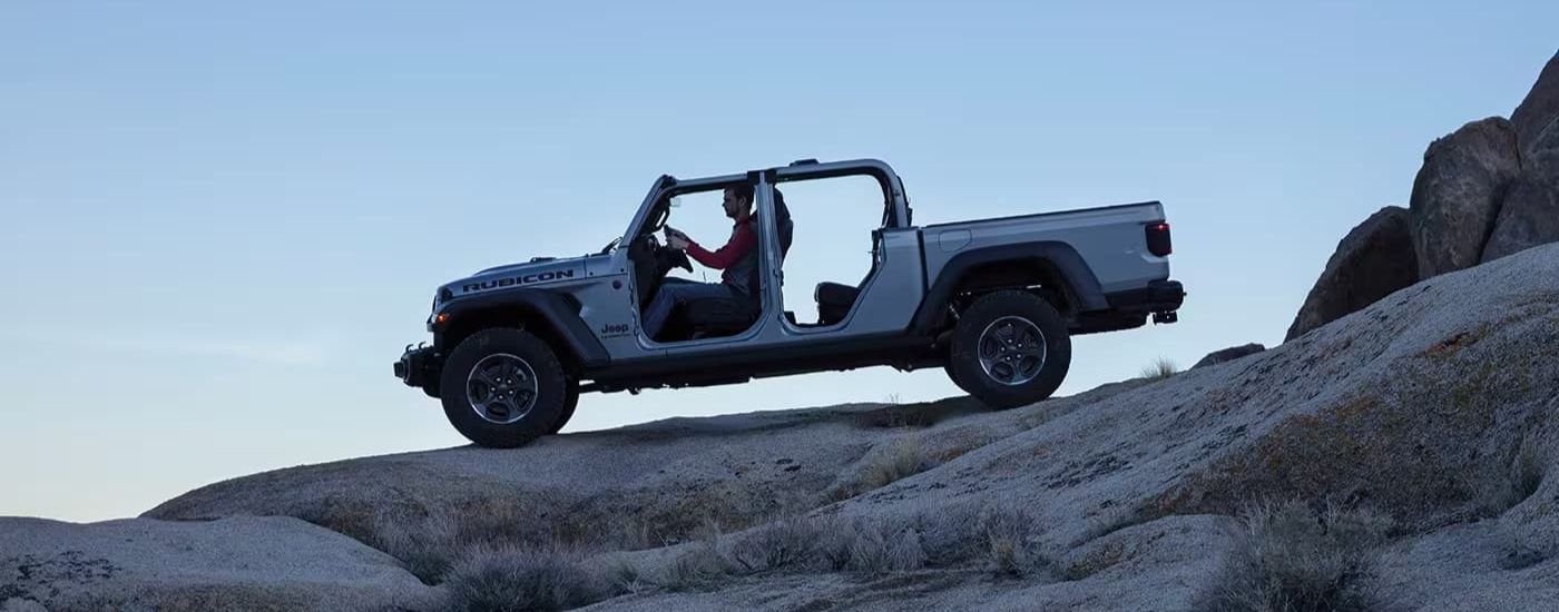 A silver 2023 Jeep Gladiator Rubicon is shown from the side off-roading.