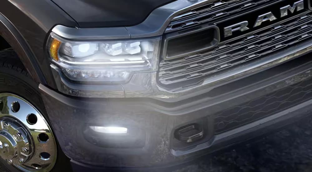 A close up of the grille on a black 2024 Ram 5500 with illuminated headlights.