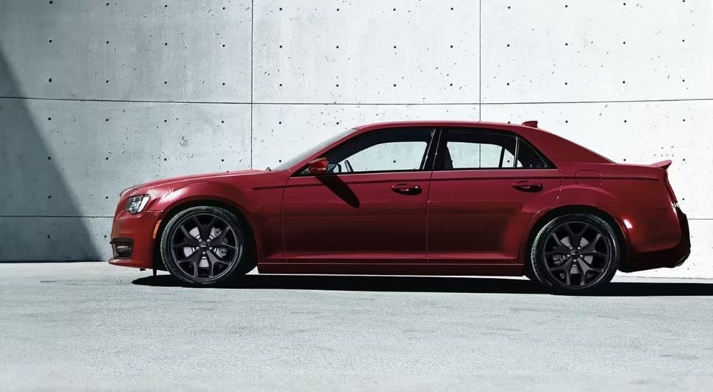 A red 2023 Chrysler 300 is shown parked near a cement wall.