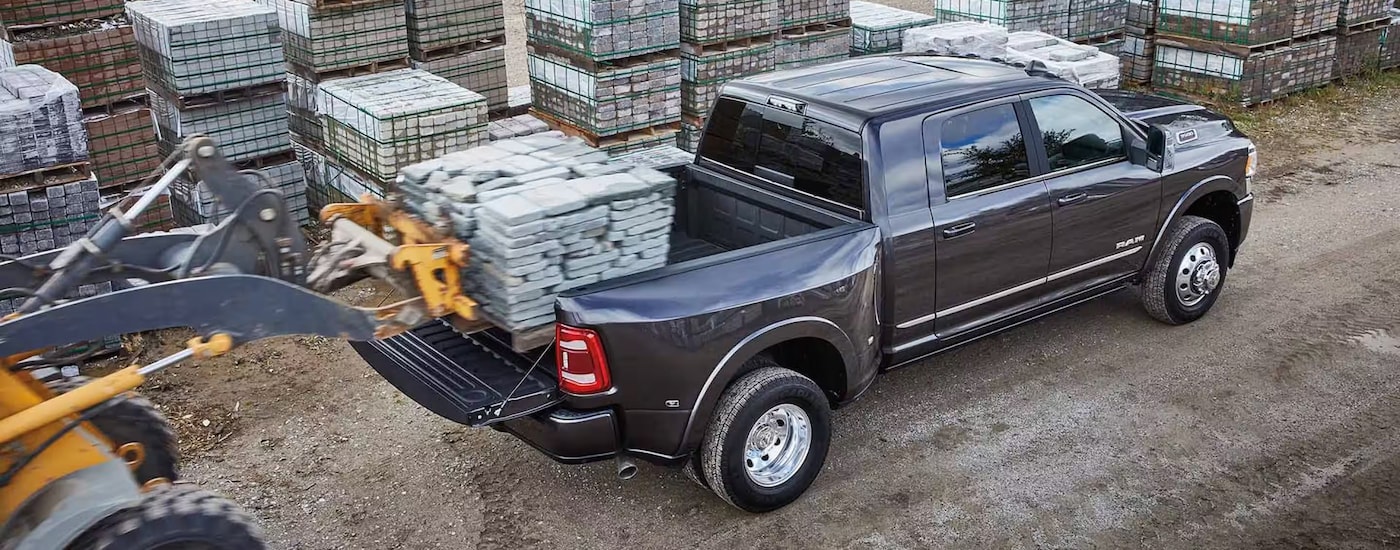 Overhead view of a tractor loading a pallet of bricks into the back of a grey 2024 Ram 3500 dually, one of many commercial vehicles for sale.