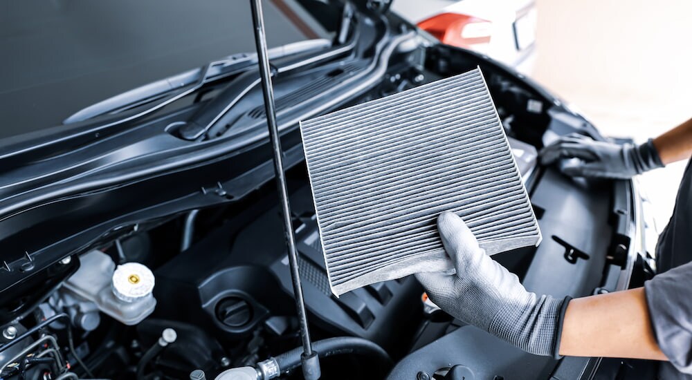 A mechanic inspecting an engine air filter at a Jeep service center.