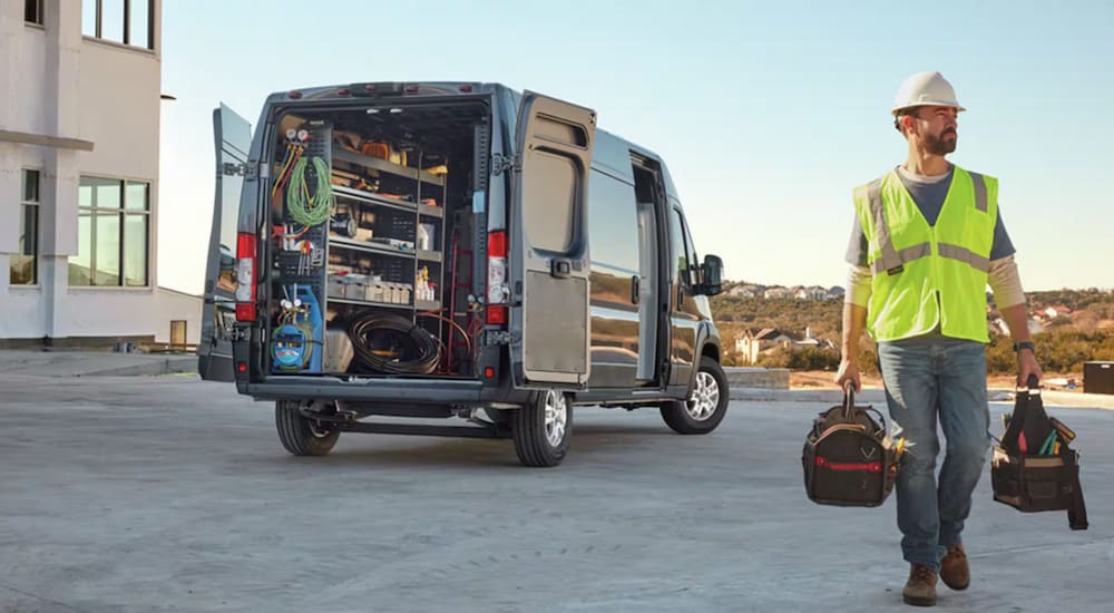 A workman walking away from an open 2024 Ram ProMaster Cargo Van filled with equimpent.