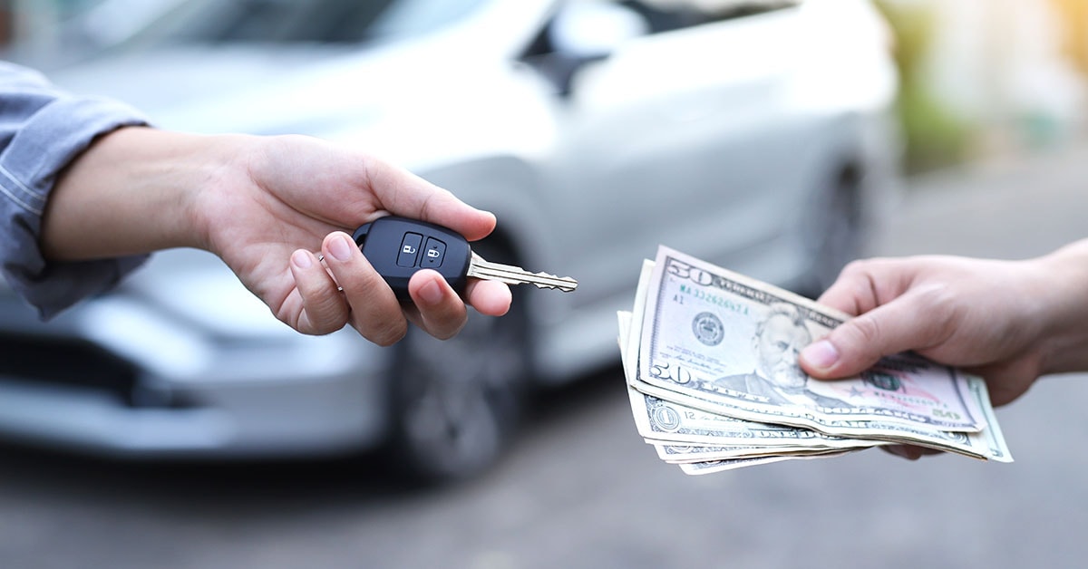 Cash and keys exchanging hands as part of GMC trade-in