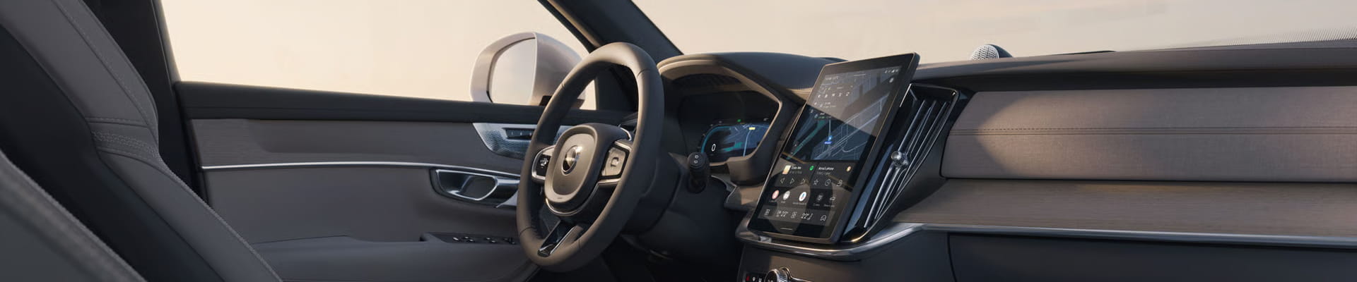 Volvo interior featuring a digital driver display, large vertical touchscreen, and modern wood-trim dashboard.