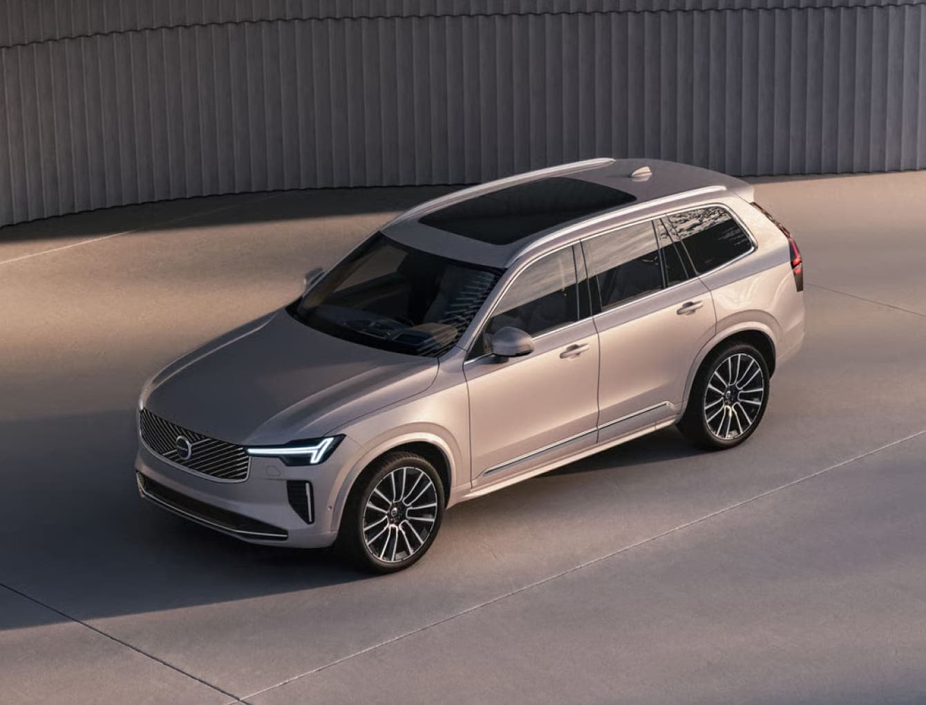 2026 Volvo XC90 SUV with sleek design and roof sunroof, parked on smooth concrete. Elegant lines and modern headlights convey a sense of luxury and sophistication.