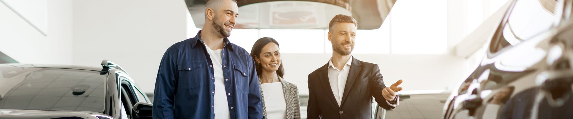 Couple speaking with a salesperson at a car dealership.