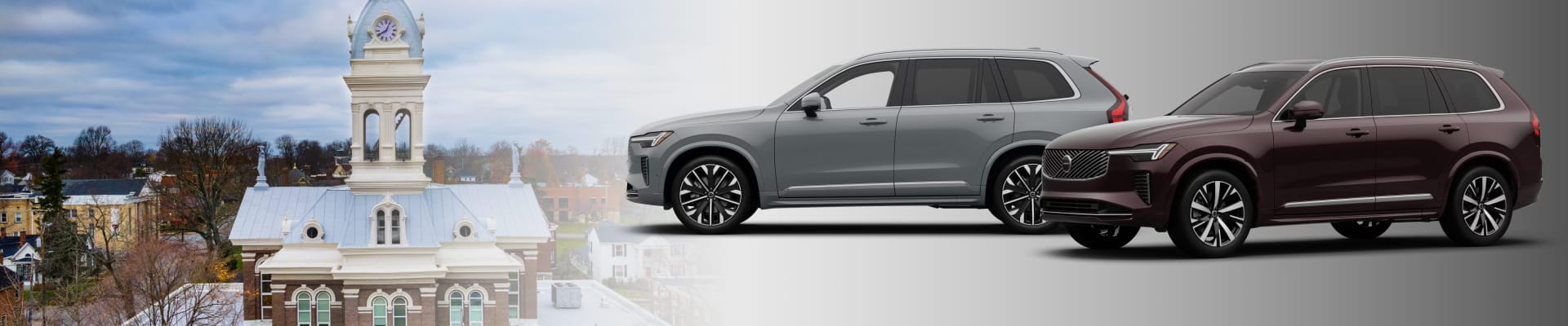Two Volvo XC90 SUVs displayed alongside a historic clock tower and surrounding town scenery.