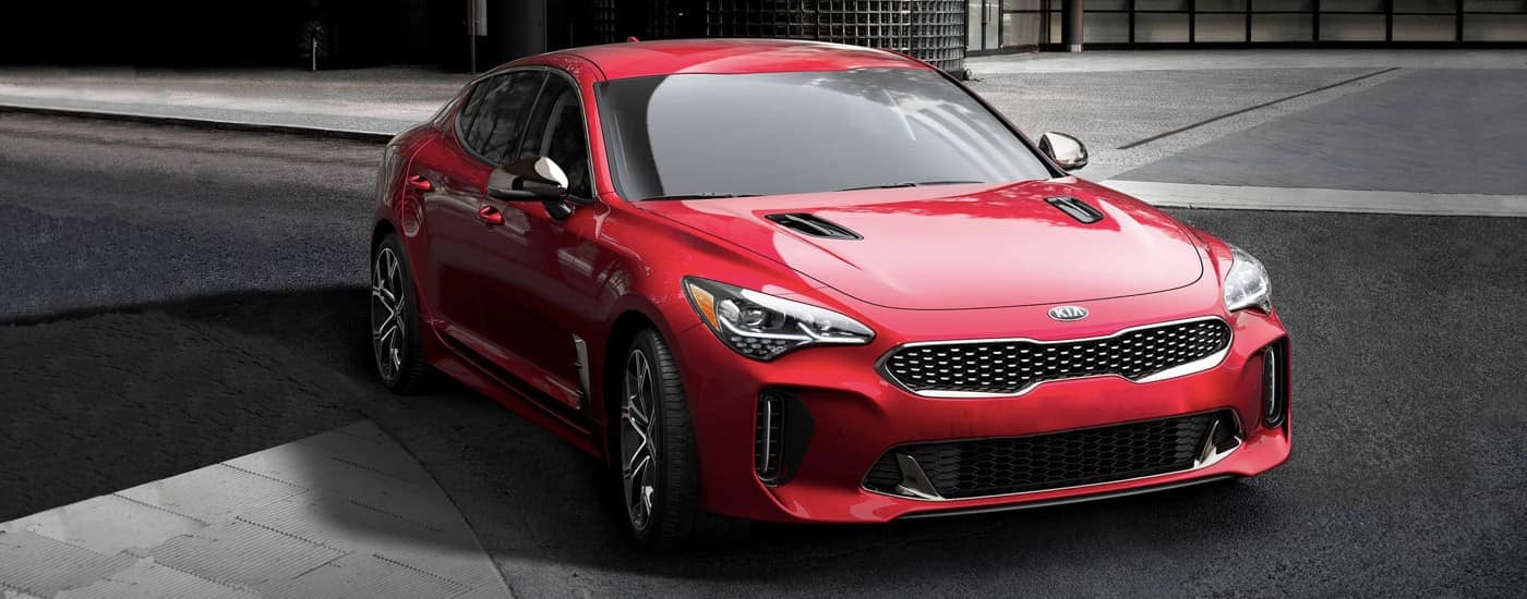 A red 2021 Kia Stinger is shown rounding a city corner.