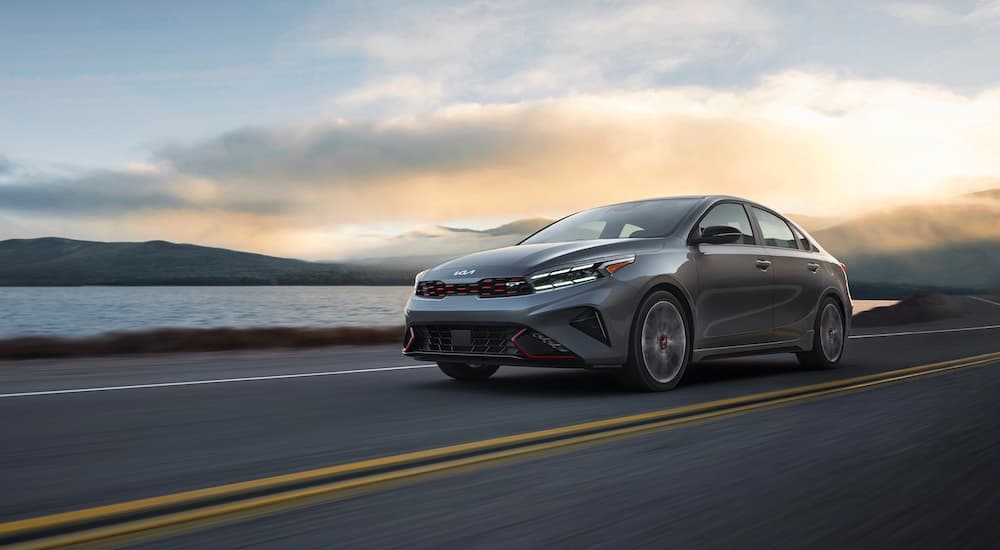 A grey 2022 Kia Forte GT is shown driving past a lake after leaving a Norristown Kia dealer.