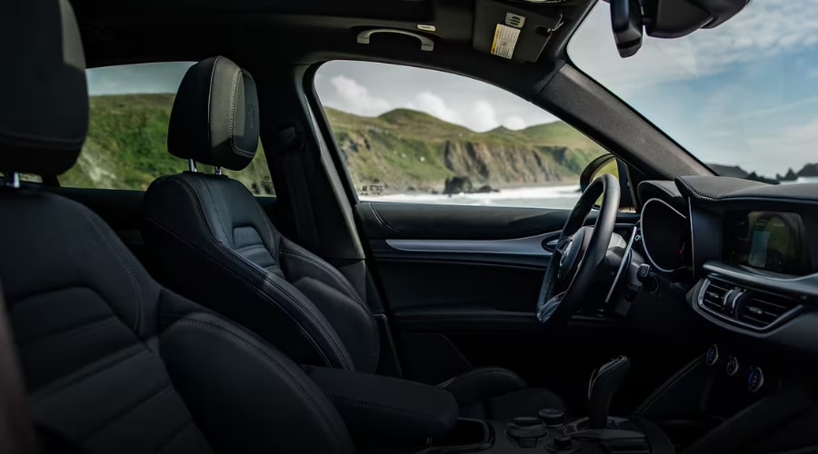 Driver-focused black leather interior cockpit of the 2026 Alfa Romeo Stelvio with column-mounted aluminum paddle shifters in Ramsey, NJ