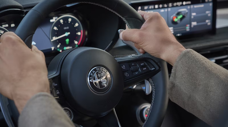 Driver holding the steering wheel of a 2026 Alfa Romeo Tonale, focusing on the 12.3-inch digital instrument cluster and touchscreen display during an autumn commute through Bergen County, NJ.