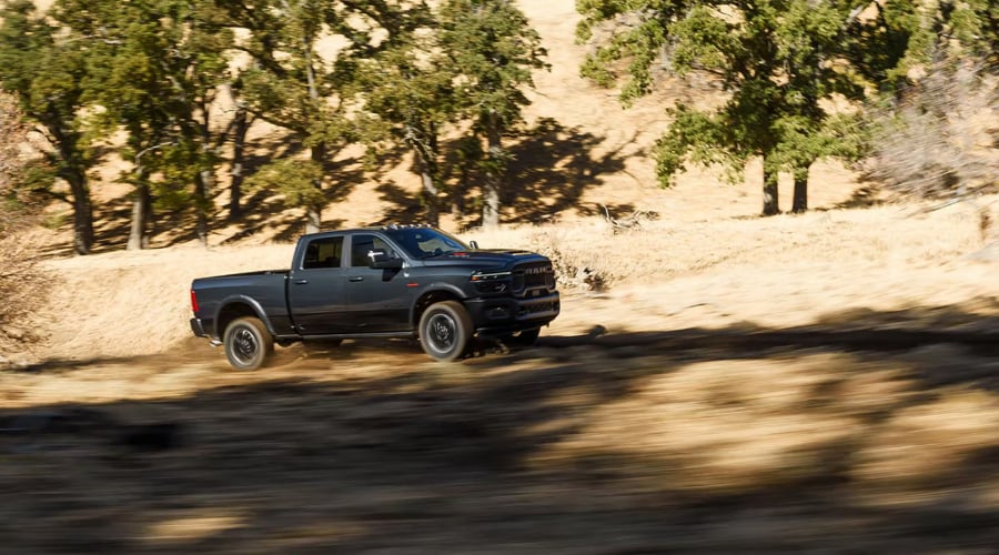 Dark gray 2026 Ram 2500 Heavy-Duty 4x4 truck driving off-road on a rugged dirt trail, demonstrating all-terrain performance and towing power for commercial fleets and recreational haulers in Ramsey, NJ and Bergen County. 
