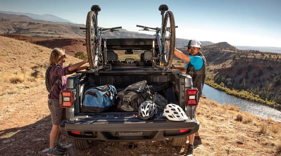 Two mountain bikes and outdoor gear loaded inside the cargo box of a 2026 Jeep Gladiator with the tailgate open, showcasing Gladiator steel truck bed dimensions for hauling recreational gear in Mahwah and Ramsey, NJ