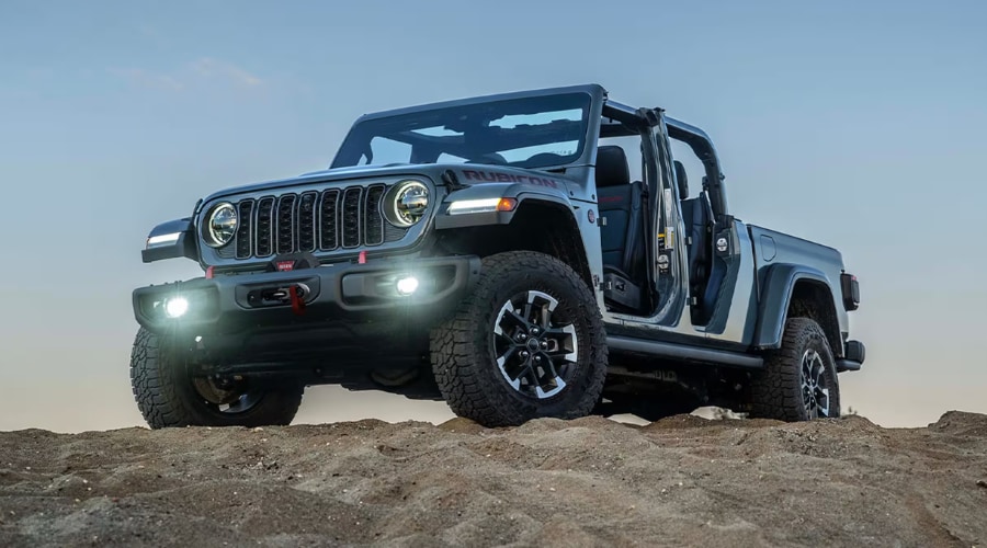 Grey 2026 Jeep Gladiator Rubicon 4WD with doors and top removed, showing off-road winch and active LED fog lights, representing open air 4x4 utility pickup capability near Route 17 and Paramus, NJ