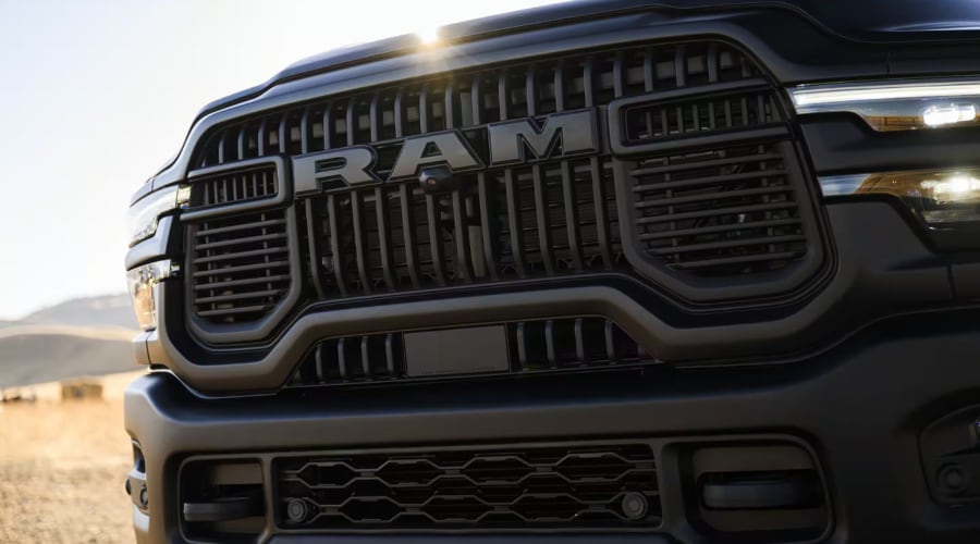 Close-up front grille detail of a matte black 2026 Ram 2500 Heavy-Duty truck highlighting bold RAM lettering, integrated front camera, and LED headlights, available for North Jersey contractors at Ramsey Chrysler Jeep Dodge Ram.