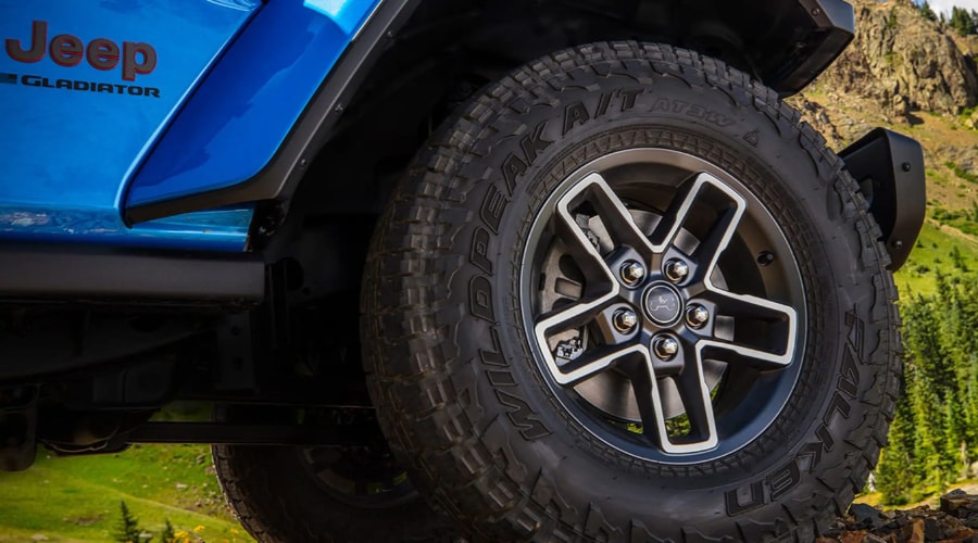 Close-up view of a Falken Wildpeak A/T all-terrain tire and 5-spoke alloy wheel mounted on a Hydro Blue 2026 Jeep Gladiator, highlighting deep tread depth and tire pressure maintenance for fall driving in Ramsey, NJ.