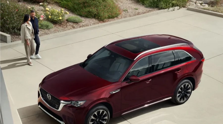 High-angle view of an Artisan Red 2026 Mazda CX-90 three-row SUV with a panoramic moonroof parked outside, perfect for Bergen County families preparing for autumn road trips from Ramsey, NJ.
