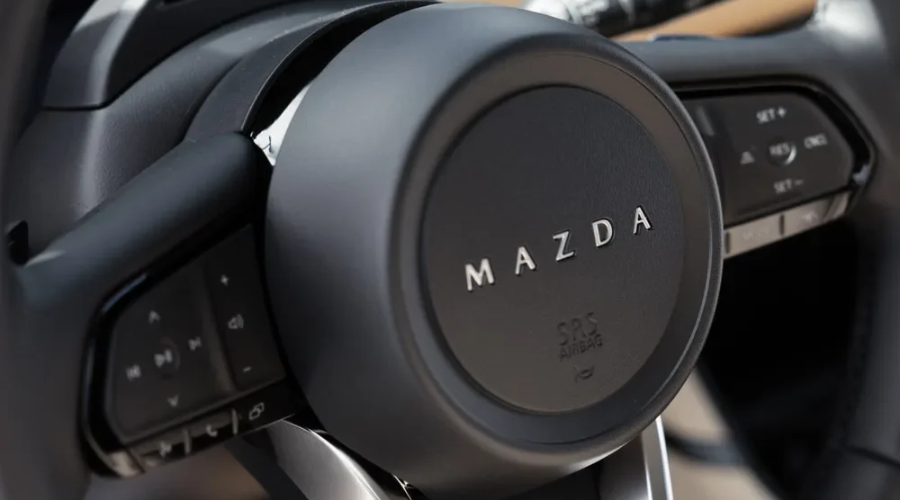 Close-up of the multi-function steering wheel in a 2026 Mazda CX-5 showcasing Mazda Radar Cruise Control buttons and integrated i-Activesense safety toggles, serviced at Ramsey Mazda in Bergen County, NJ