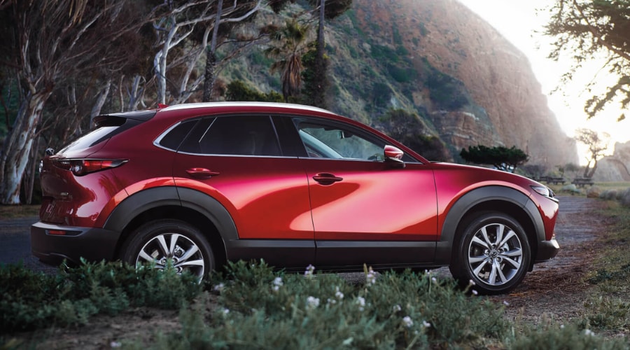 Side profile view of a Soul Red 2026 Mazda CX-30 featuring protective lower body cladding and silver alloy wheels, highlighting compact crossover agility for Bergen County and Spring Valley commuters.