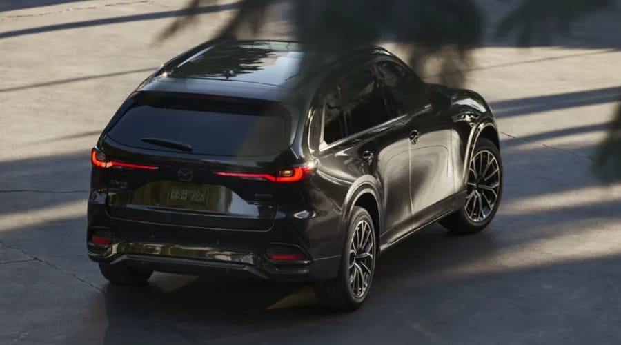 High-angle rear quarter view of a black 2026 Mazda CX-70 crossover with illuminated LED taillights, showcasing its wide stance and all-weather capability for autumn commutes in Ramsey, NJ.