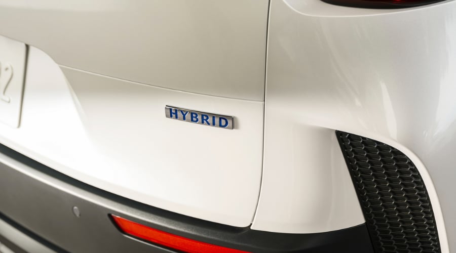 Close-up view of the chrome and blue Hybrid emblem on the rear tailgate of a white 2026 Mazda CX-50 Hybrid available in Ramsey, NJ.