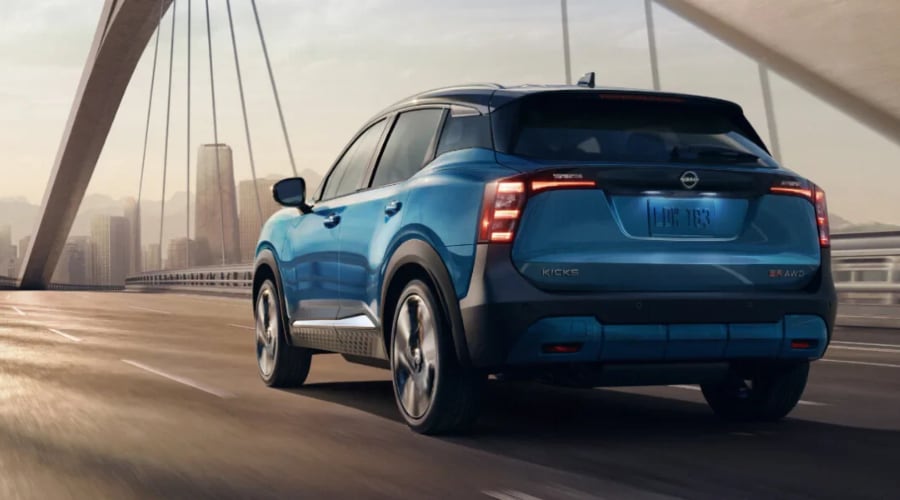 Blue 2026 Nissan Kicks with Intelligent AWD driving across a bridge toward an urban skyline, highlighting its confident highway stability and traction for daily commuters in northern New Jersey.