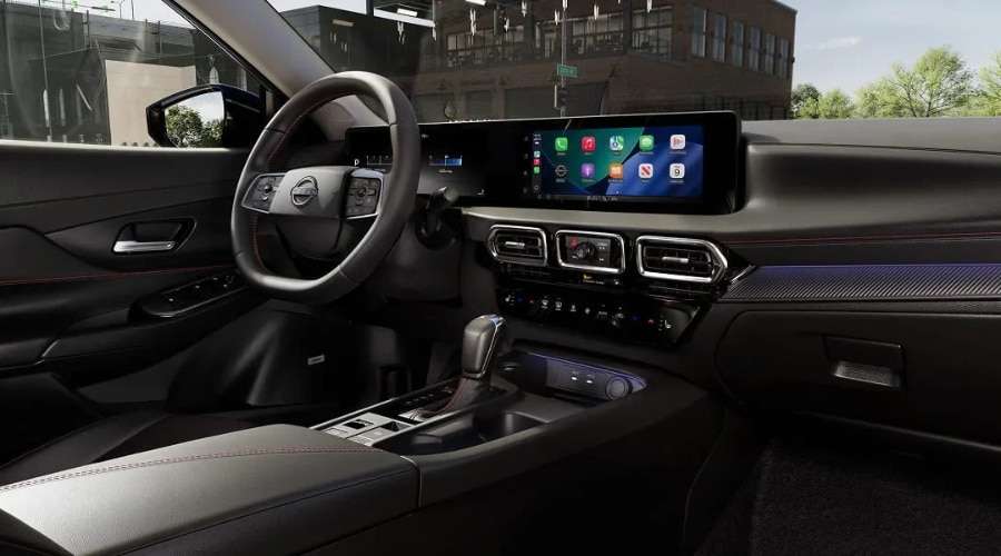 Dashboard overview of the 2027 Nissan Sentra featuring the standard 12.3-inch touchscreen display running wireless Apple CarPlay, red contrast stitching, and carbon-look trim, available at Ramsey Nissan in Ramsey, NJ.