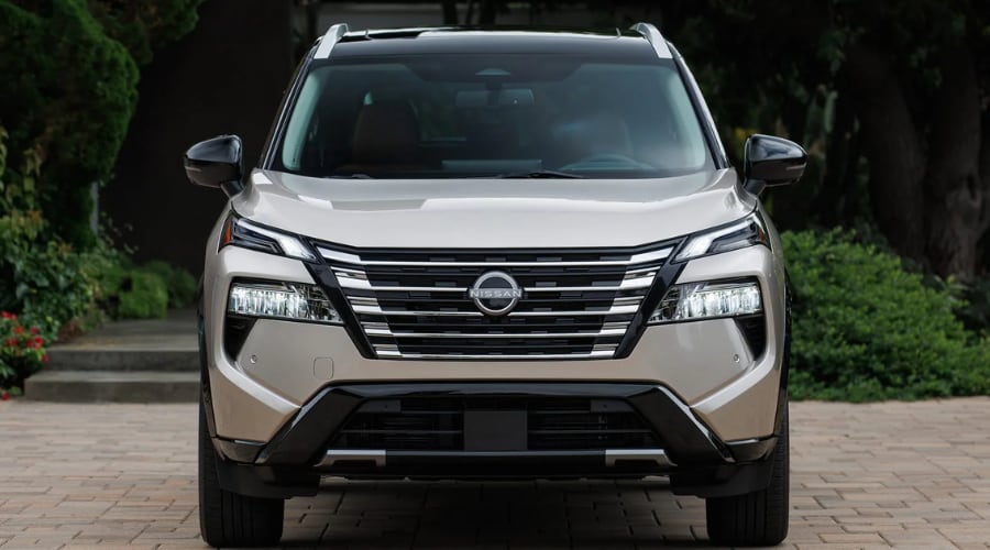 Direct front view of a champagne gold 2026 Nissan Rogue showing the front emblem radar sensor, LED headlights, and windshield camera housing for Safety Shield 360 maintenance at Ramsey Nissan in Bergen County, NJ.