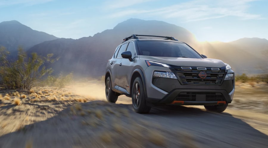 2026 Nissan Rogue SUV with roof rails driving along an off-road trail on a weekend getaway trip for Bergen County drivers