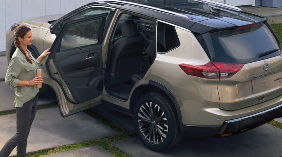 A family preparing to enter a gold and black two tone 2026 Nissan Rogue showing the wide open rear passenger door for easy cabin access on a residential driveway