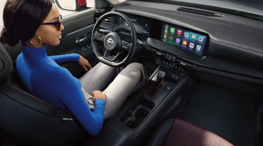 Driver sitting inside the modern digital cockpit of a 2026 Nissan Kicks featuring dual 12.3-inch monolith displays and wireless Apple CarPlay, designed for comfortable fall commutes across Ramsey, NJ and Bergen County.