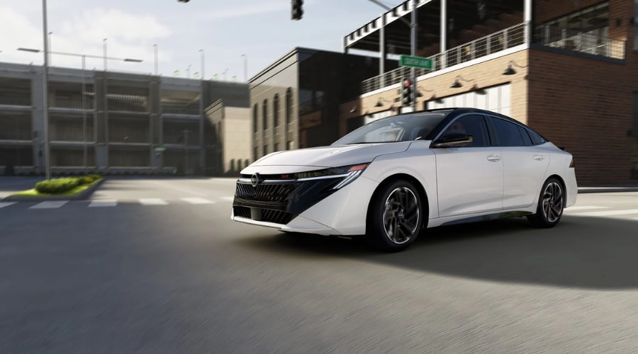 White 2026 Nissan Sentra SR sedan with a two-tone black roof, 18-inch alloy wheels, and dark chrome grille driving through a suburban Bergen County street near Ramsey and Paramus, NJ.