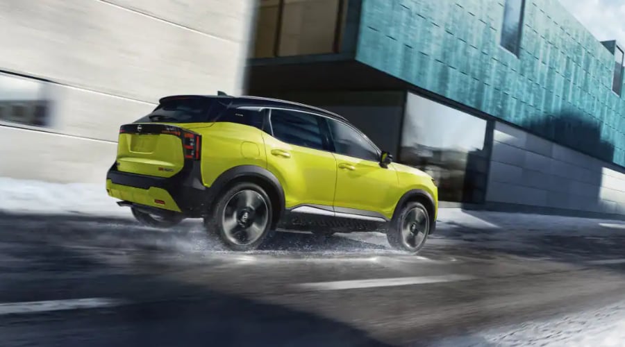 Side profile profile of a 2026 Nissan Kicks executing a turn on wet asphalt near Paramus shopping districts