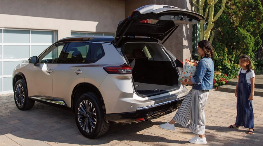 Mother using the motion-activated power liftgate on a 2026 Nissan Rogue while carrying shopping bags in a suburban Ramsey NJ driveway