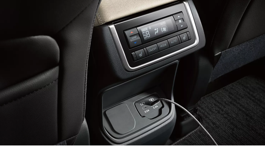 Close-up of the rear center console in the 2027 Subaru Ascent interior showing automatic climate control displays, heated rear seat buttons, and dual USB charging ports with a plugged-in cable at Ramsey Subaru in Bergen County, NJ.