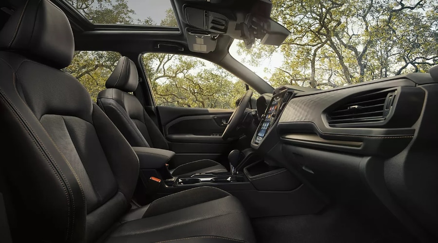 Front cabin interior of a 2026 Subaru Forester featuring dark leather-trimmed seats, climate control air vents, panoramic sunroof, and EyeSight camera enclosure at the top of the windshield in Ramsey, NJ