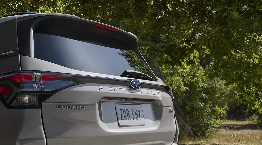 Rear tailgate view of a silver 2026 Subaru Forester showing the rear windshield wiper, Symmetrical AWD badge, and embossed Forester lettering under autumn trees in Ramsey, NJ