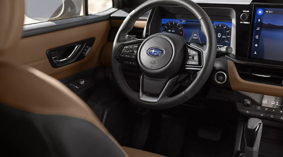 Driver side view of a 2026 Subaru Outback interior with two-tone tan and black leather upholstery, showing the multi-function leather-wrapped steering wheel, digital instrument cluster, and center touchscreen display set up for daily Route 17 commuting in Bergen County, NJ.
